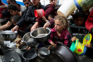 FILE PHOTO: Palestinian children wait to receive food cooked by a charity kitchen amid shortages of food supplies, in Rafah